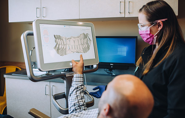 dental staff member discussing images of a patient's mouth with the patient
