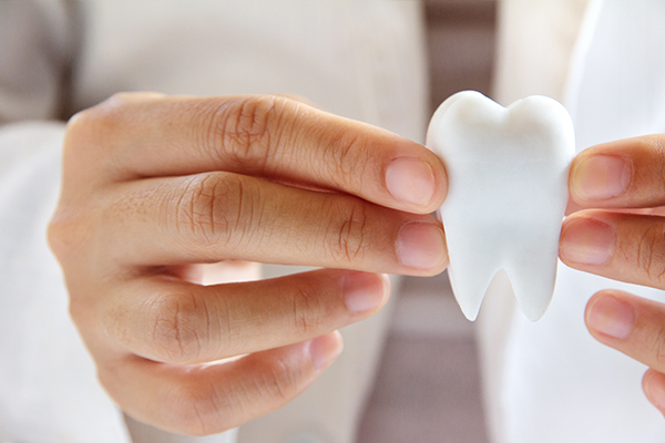 person holding up a large, fake tooth