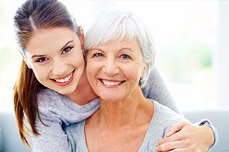 younger woman with her arm around an older woman smiling