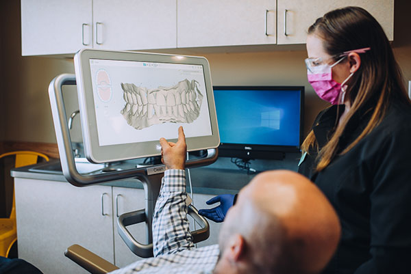 dental staff member discussing images of a patient's mouth with the patient